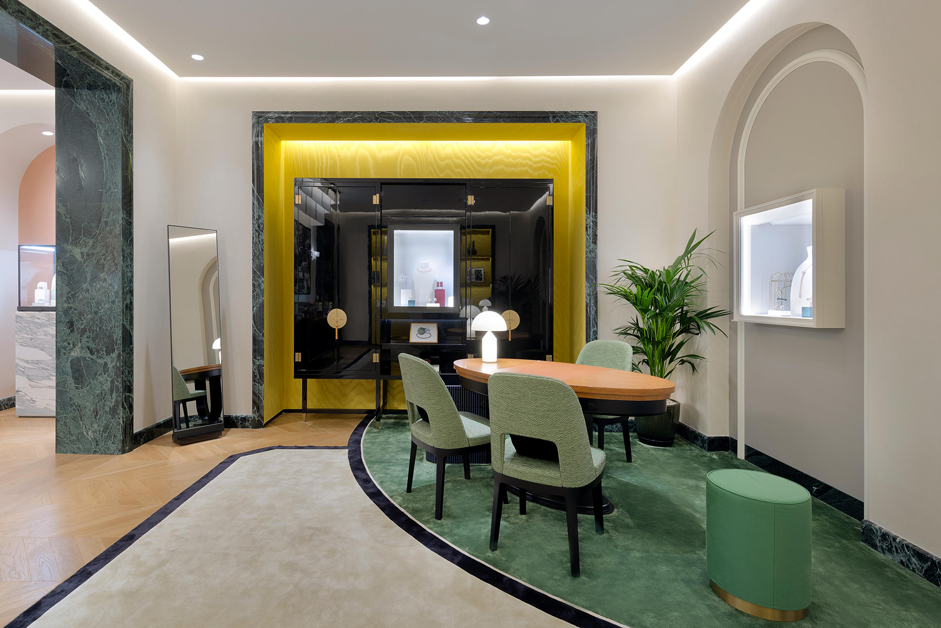 Salle de vente avec chaises vertes, table ronde et détails en marbre dans la boutique Boucheron de Koweït.