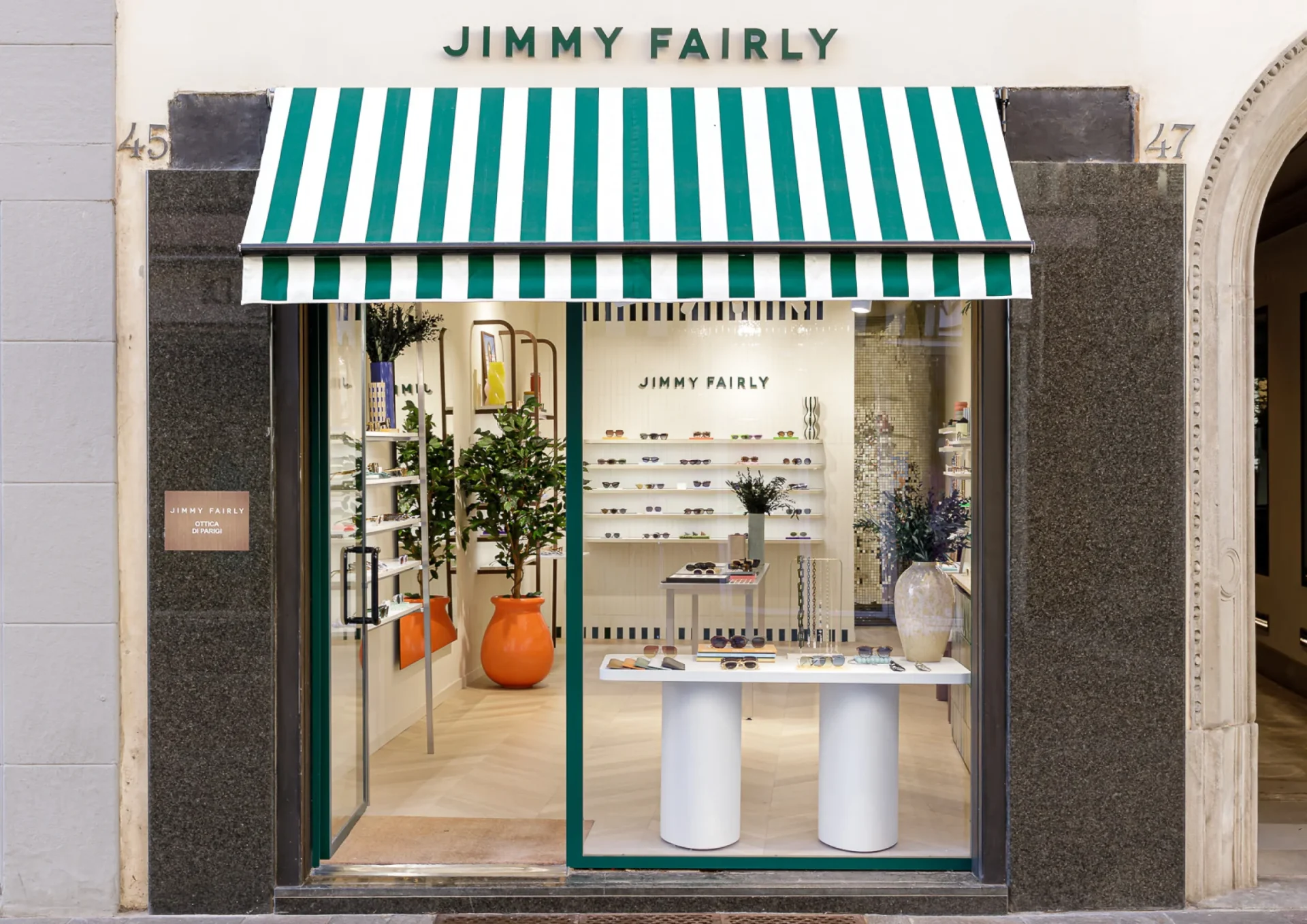 La store rayé et l'enseigne en lettrage découpé vert de l'enseigne habillant la facade le la boutique Jimmy Fairly de Bergame.