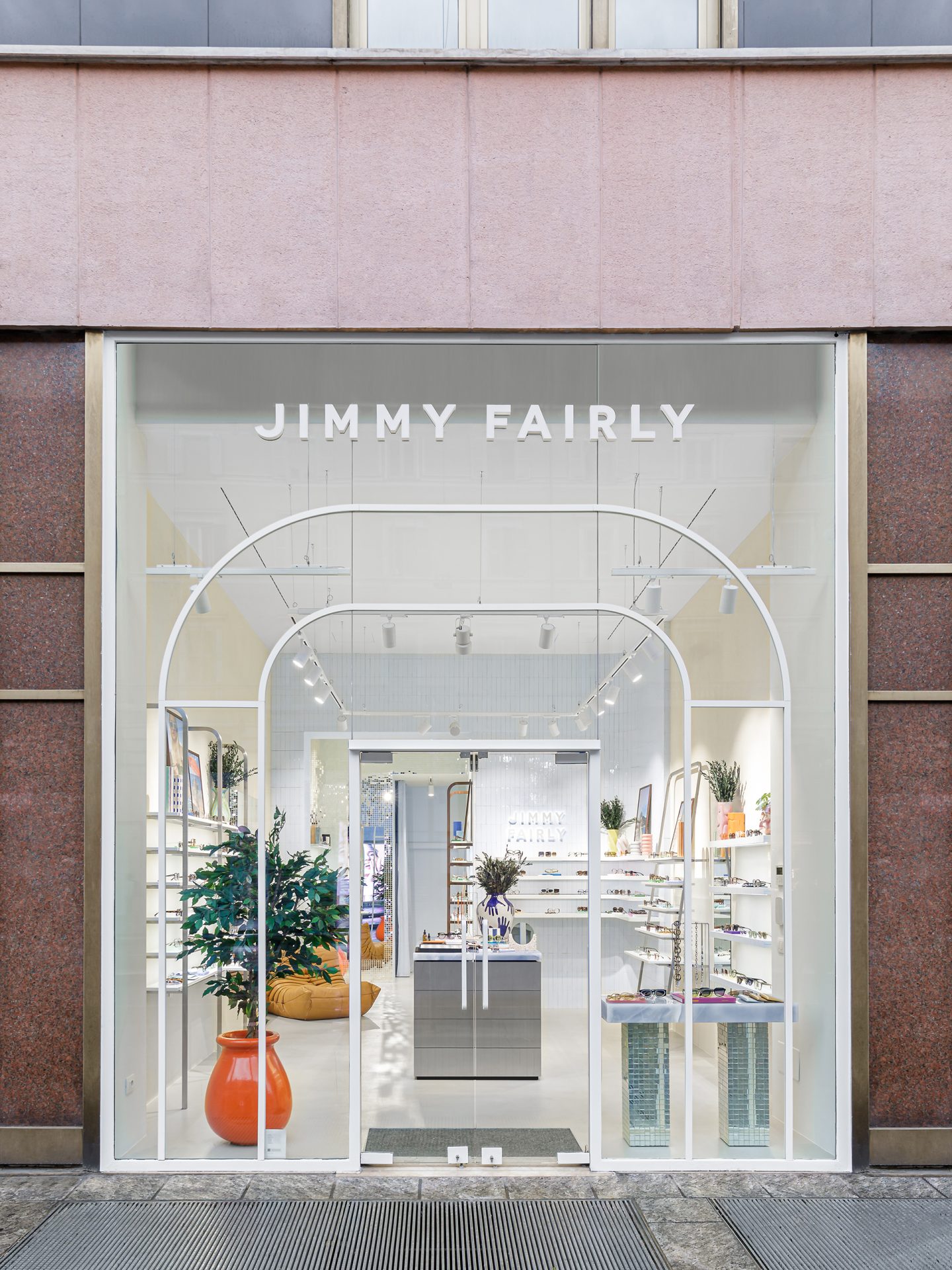 Façade vitrée avec arches blanches et présentoirs à lunettes dans la boutique Jimmy Fairly.