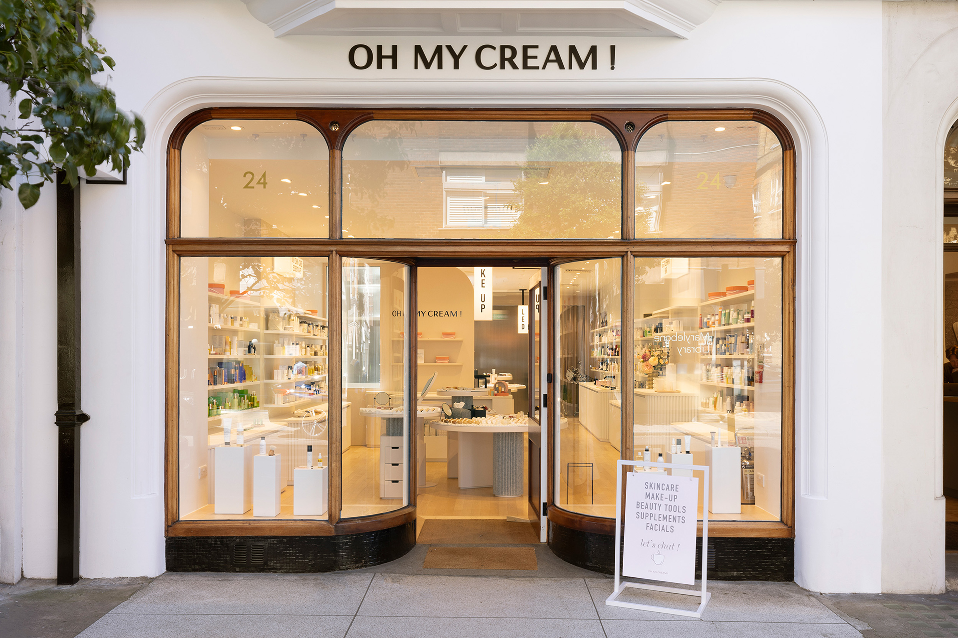 Façade avec grandes vitrines exposant des produits de beauté et un panneau sur le trottoir, dans la boutique Oh My Cream !.