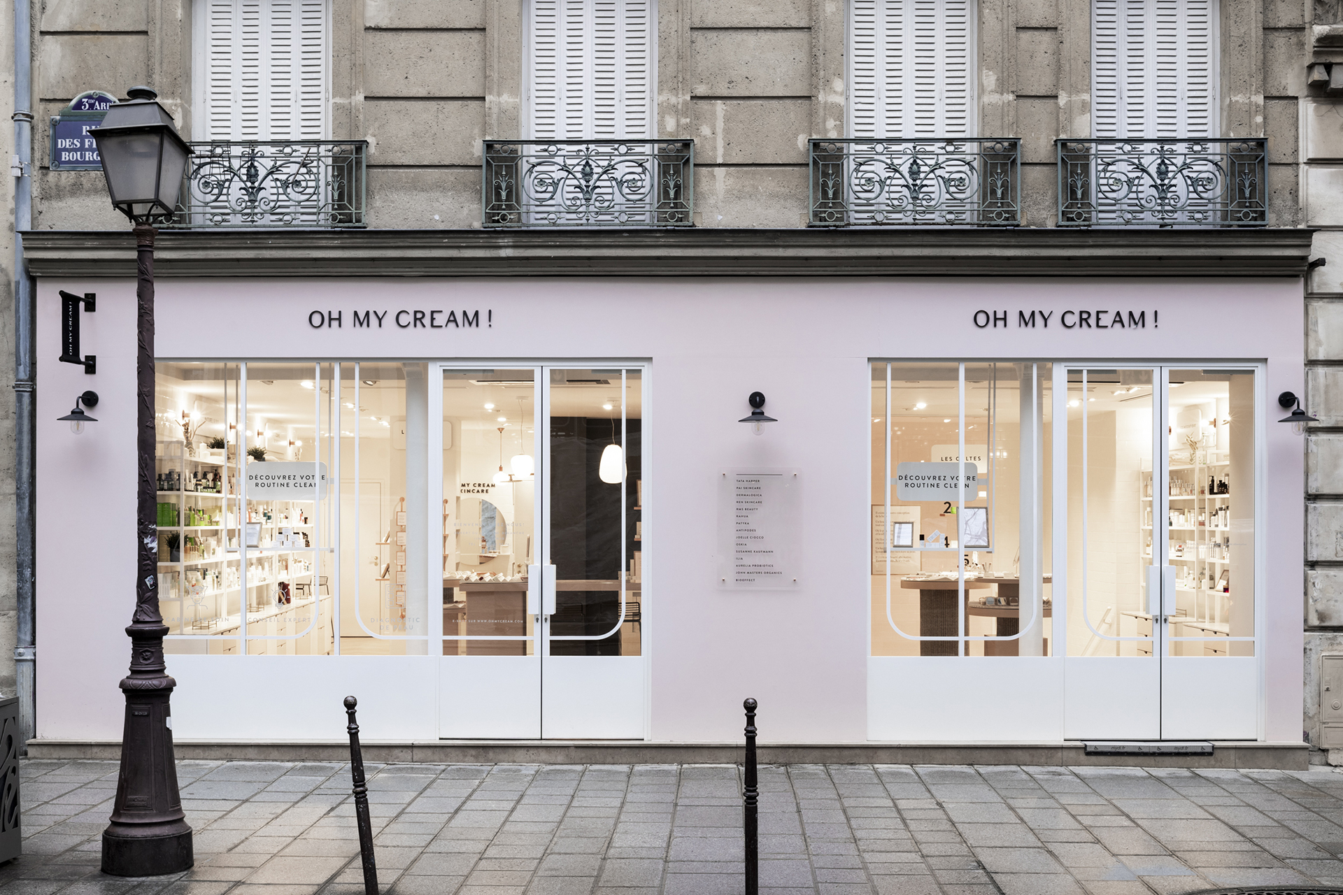 Façade avec grandes vitrines, portes blanches et extérieur rose pâle dans la boutique Oh My Cream !.