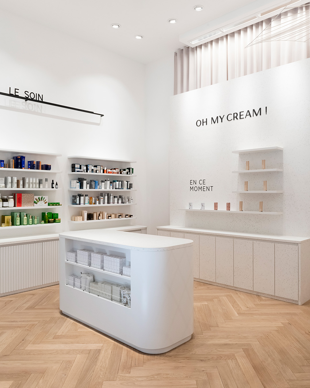 Intérieur moderne avec étagères blanches, sol en bois clair et produits soigneusement exposés dans la boutique Oh My Cream de Strasbourg.