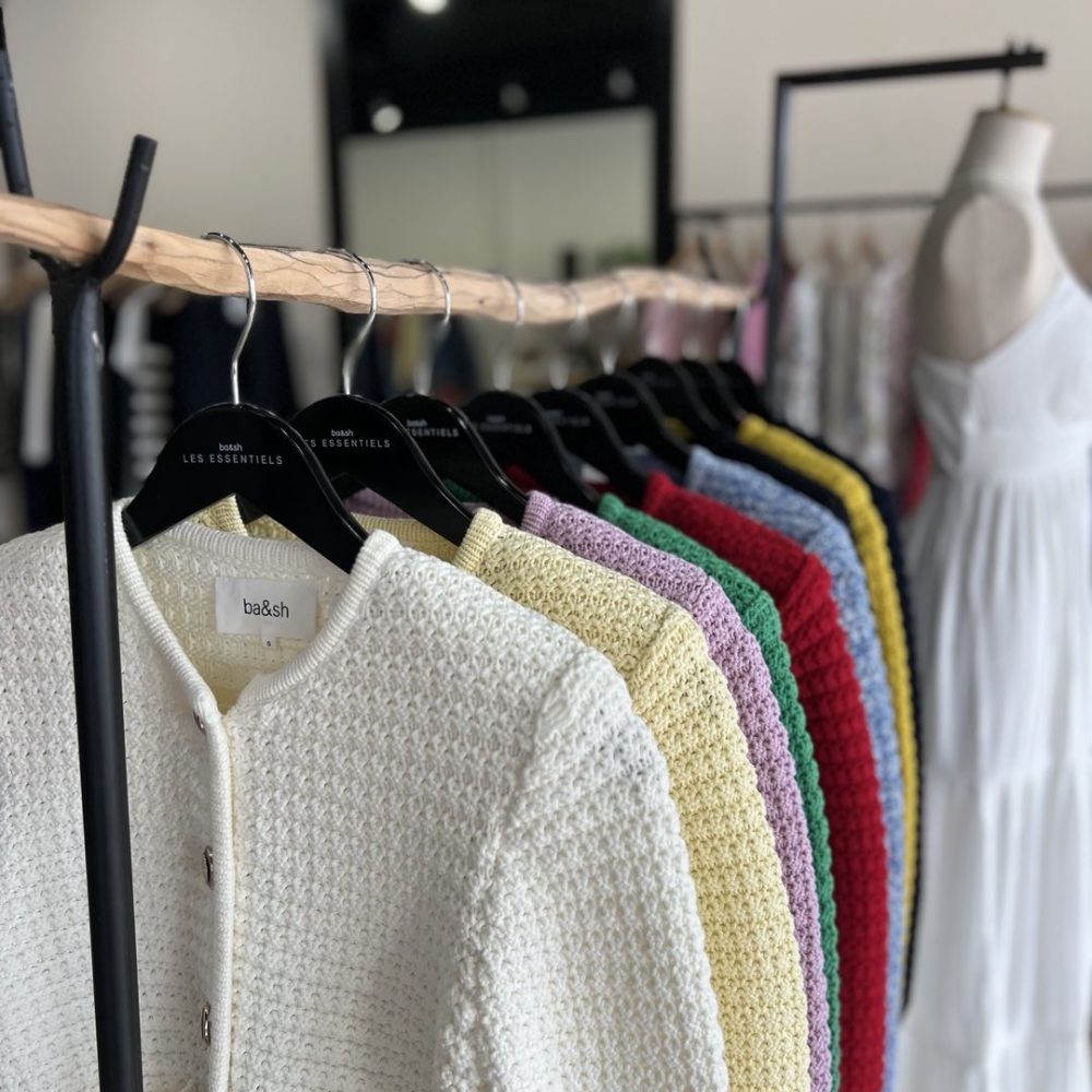 Un portant avec des cardigans colorés : blanc, jaune, , projet d'architecture pour la marque de retail de luxe ba&sh à Greenwich