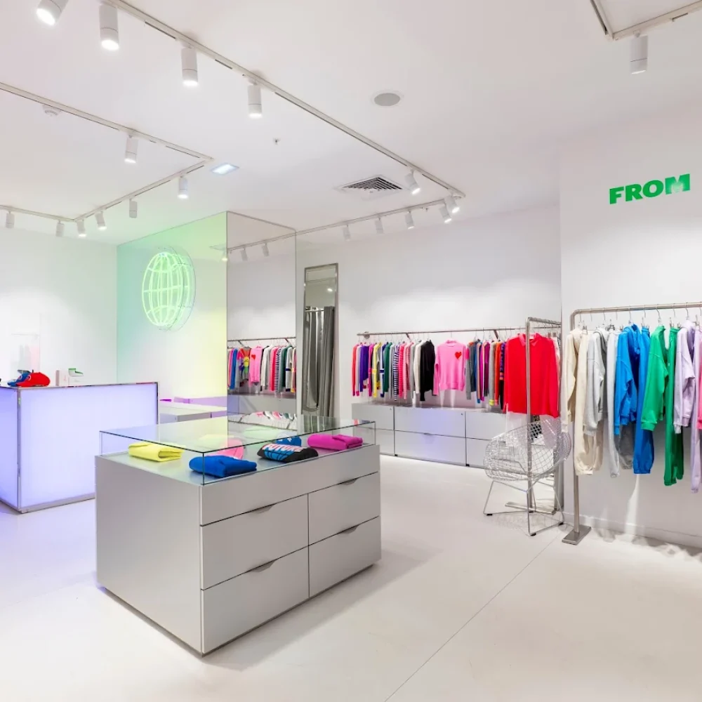 Intérieur lumineux avec des vêtements colorés sur des portants et pulls pliés, dans le shop-in-shop de la marque de prêt à porter From Future aux galleries Lafayette à Paris.