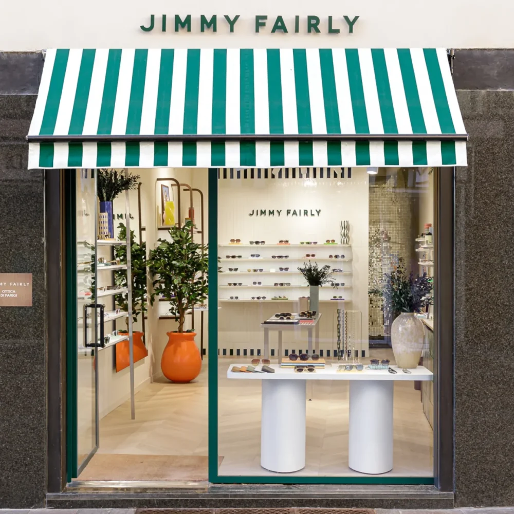 La store rayé et l'enseigne en lettrage découpé vert de l'enseigne habillant la facade le la boutique Jimmy Fairly de Bergame.