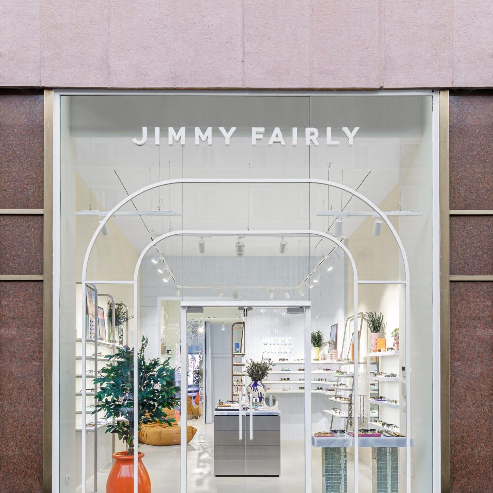 Façade vitrée avec arches blanches et présentoirs à lunettes dans la boutique Jimmy Fairly.