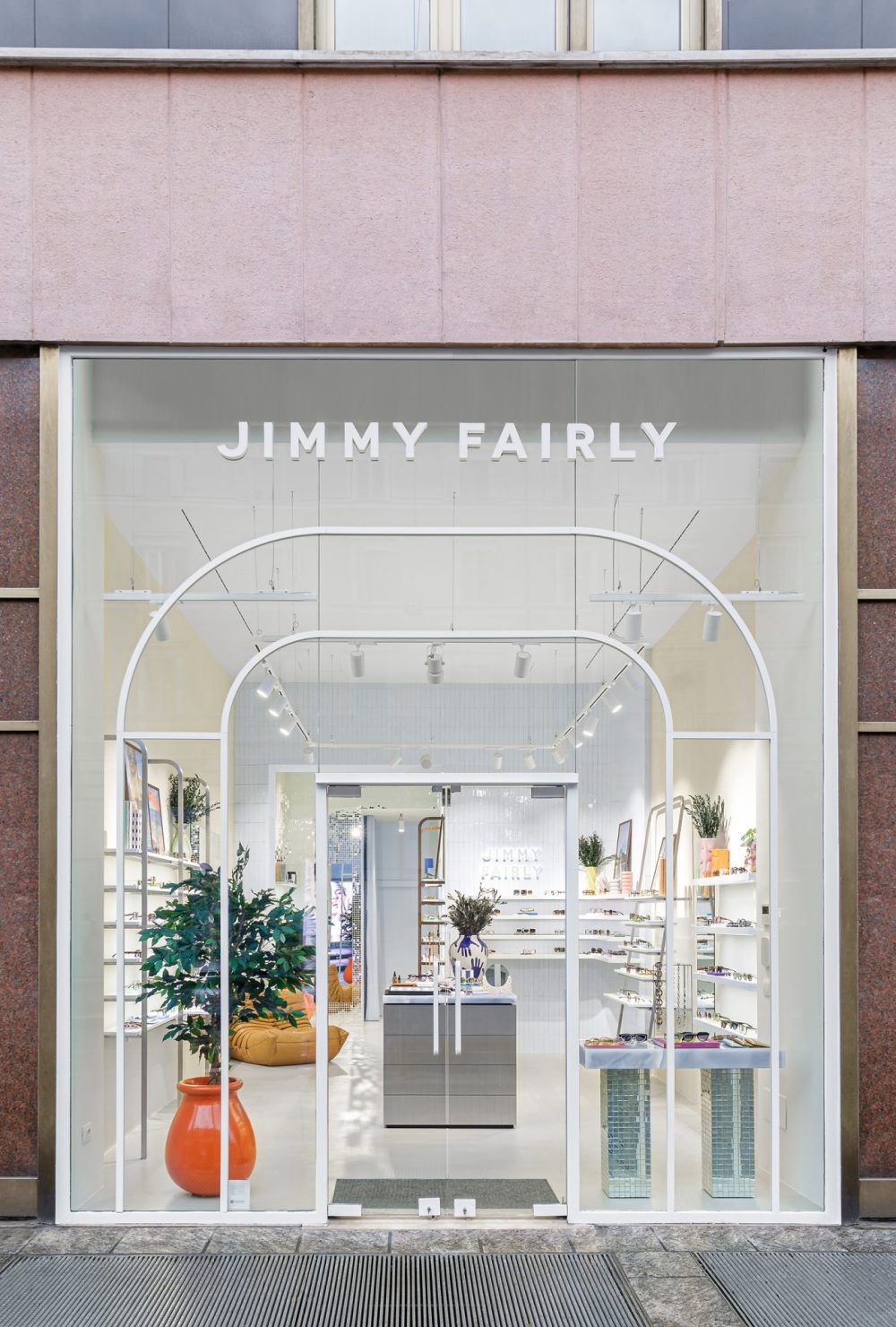 Façade vitrée avec arches blanches et présentoirs à lunettes dans la boutique Jimmy Fairly.