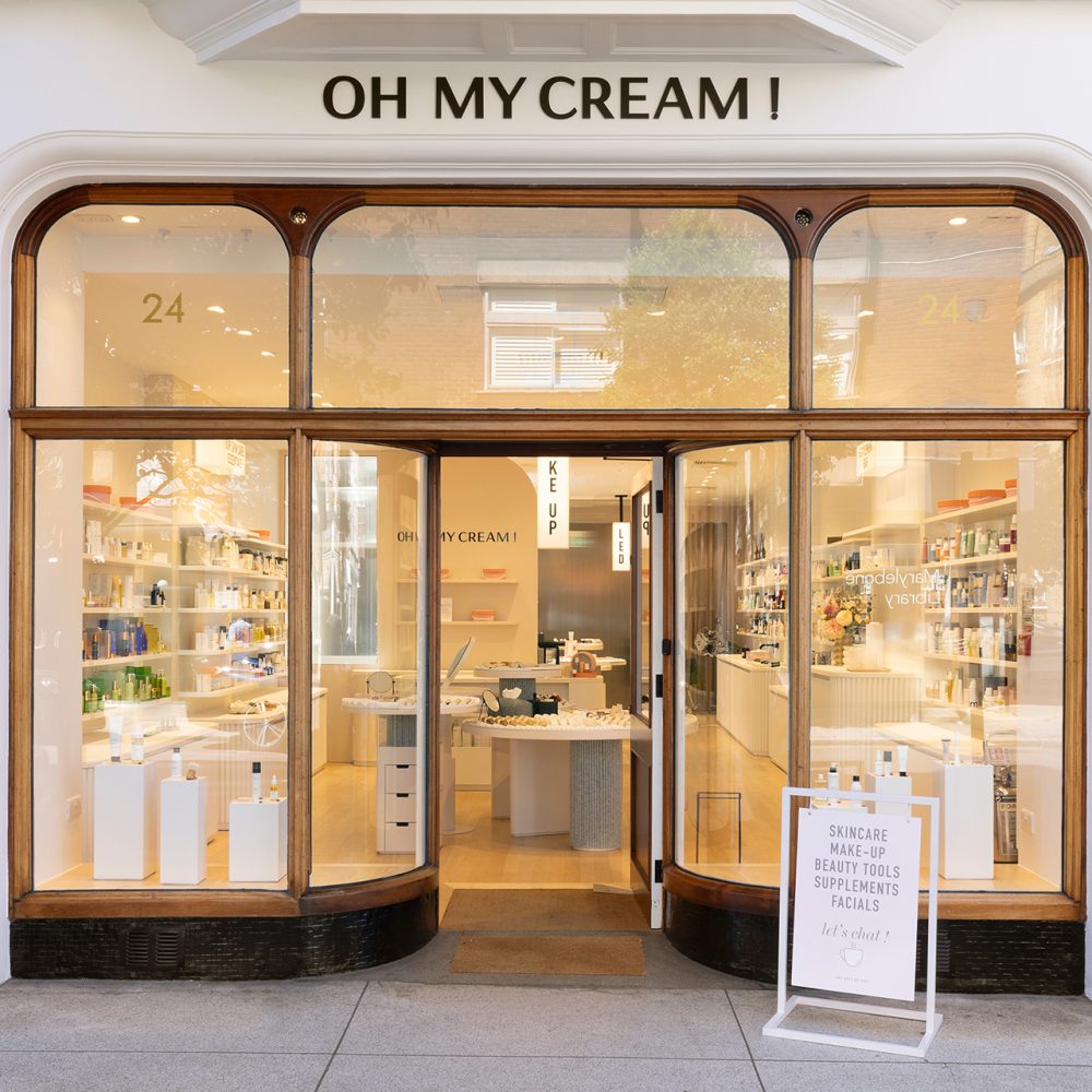 Façade avec grandes vitrines exposant des produits de beauté et un panneau sur le trottoir, dans la boutique Oh My Cream !.