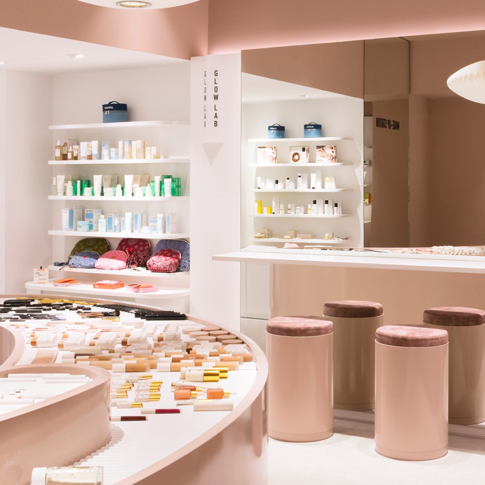 Intérieur moderne avec comptoirs courbés, tabourets et étagères de soins, décor rose doux, dans la boutique Oh My Cream ! à Paris.