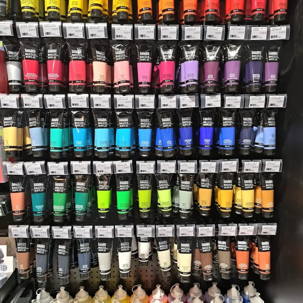 Rayonnage avec des tubes de peinture acrylique alignés sur les étagères dans la boutique Rougier&Plé Italie 2 de Paris.