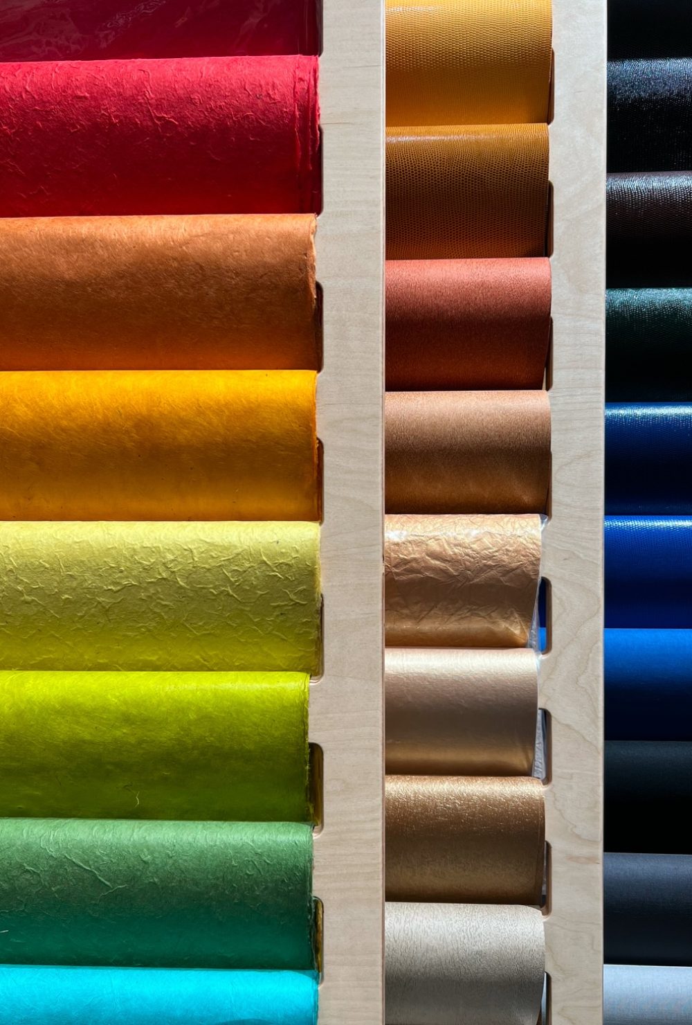 Rayonnage coloré avec des rouleaux disposés par teintes vives dans la boutique Rougier&Plé de Marseille.