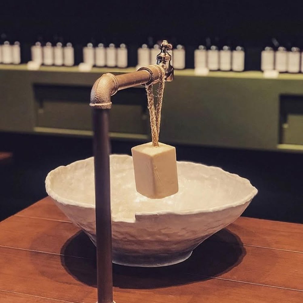 Un savon suspendu au robinet décoratif devant une vasque sculptée dans la boutique LA:BRUKET de Séoul.